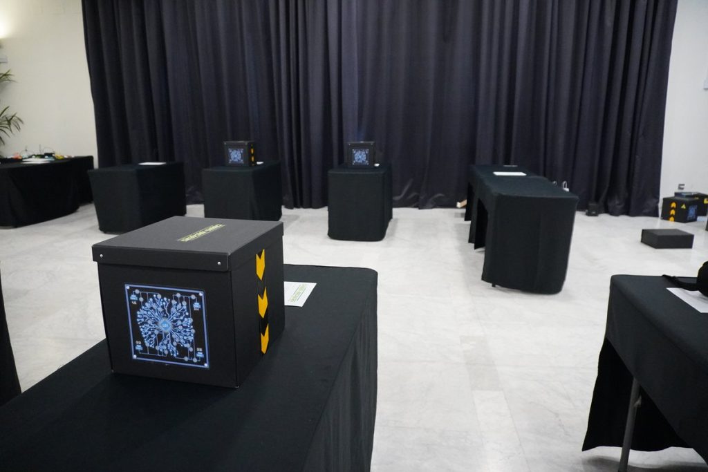 Gamificación para eventos con un escape room por mesas: sala preparada con una caja de Cybercorp en cada mesa